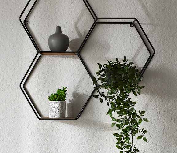 a metal hexagon shelf with a vase and a plant hanging on a wall